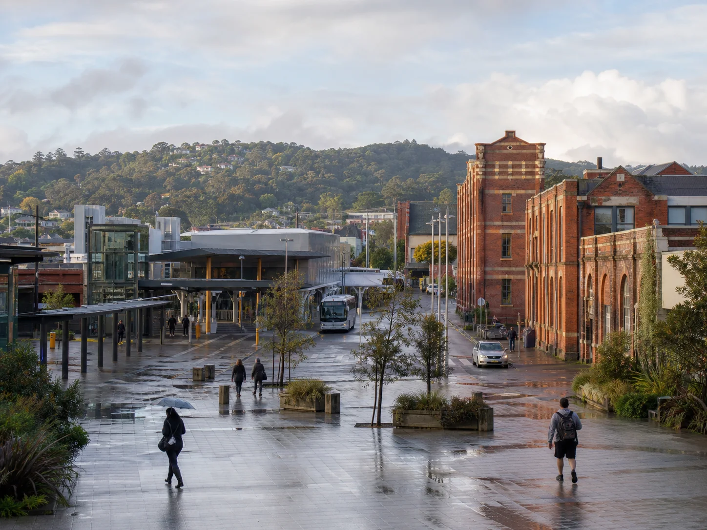 New Lynn town centre after rain with brick heritage buildings, its transport interchange and the Waitākere foothills